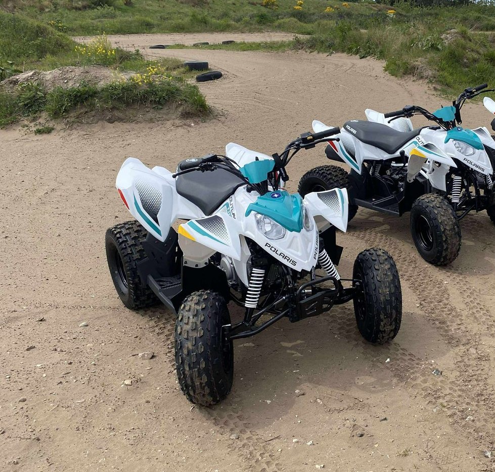 Ung kører på en Polaris Phoenix på den solbeskinnede sandbane