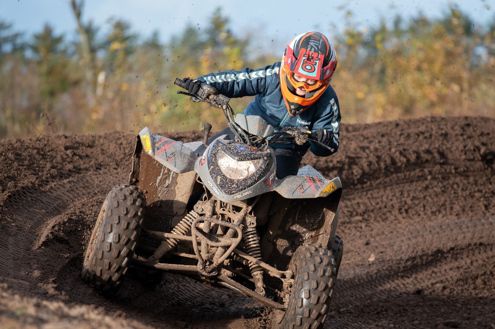 Kører i fart gennem mudderet på en Polaris ATV med orange hjelm