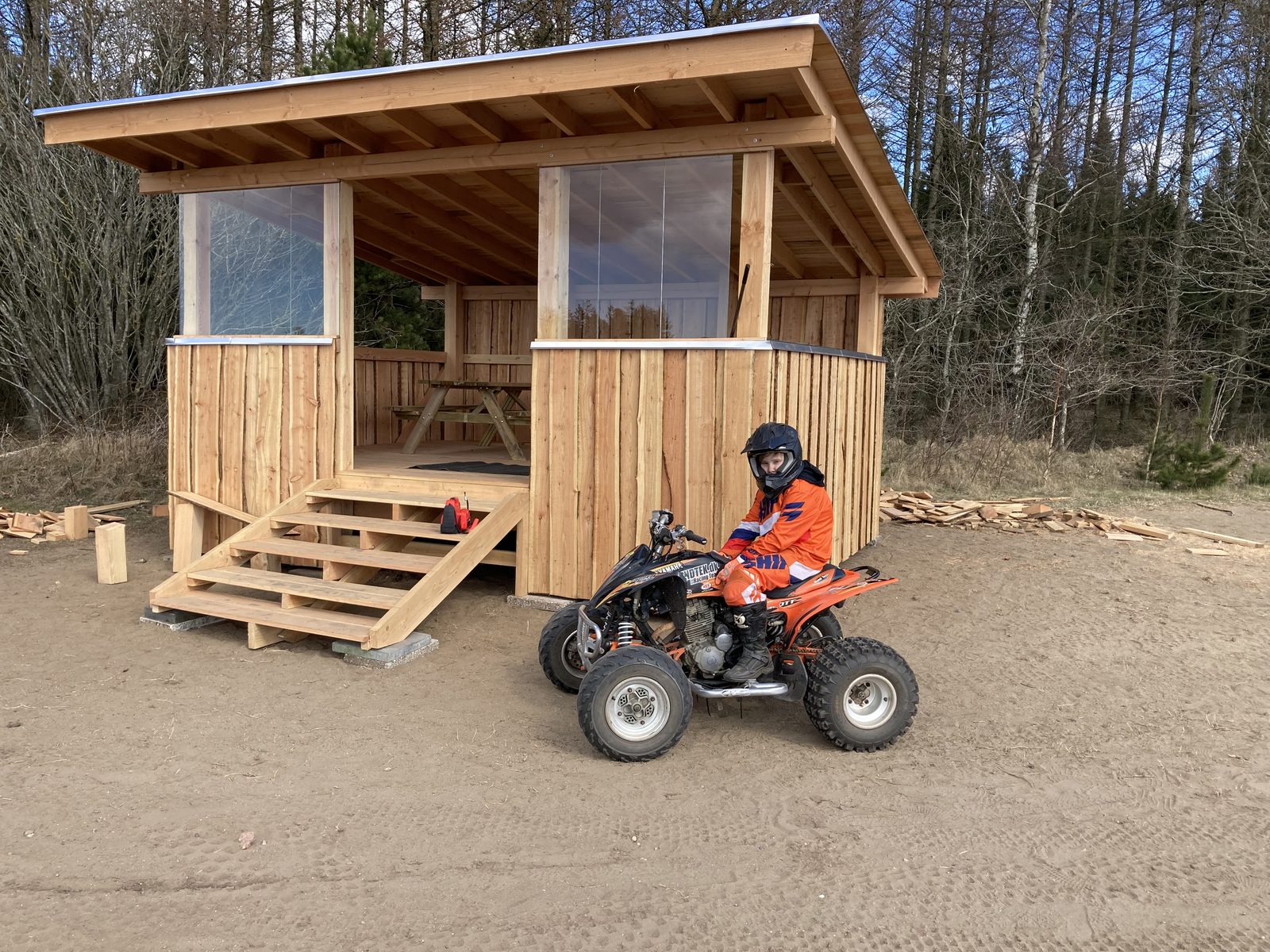 Kører i orange tøj foran den nye træpavillon ved banen
